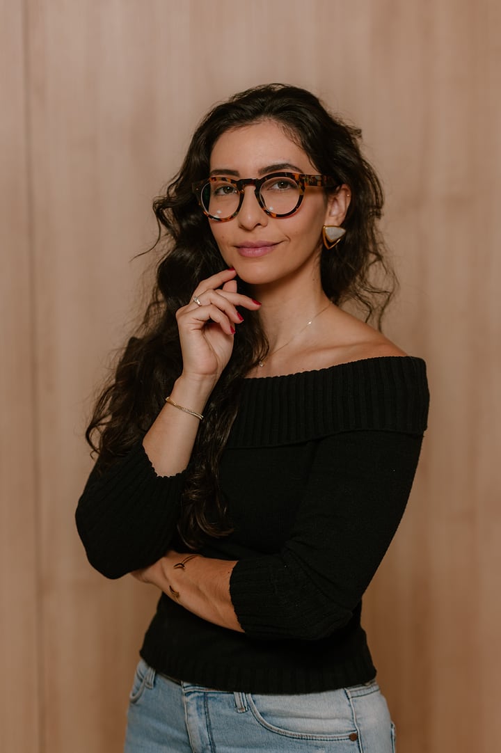Ana Luiza de óculos, com a mão no queixo